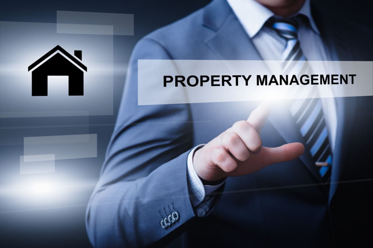 A businessman pointing to the word property management next to a house symbol