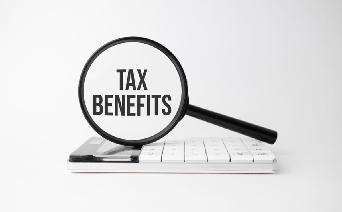 A magnifying glass on top of a calculator with the words tax benefits