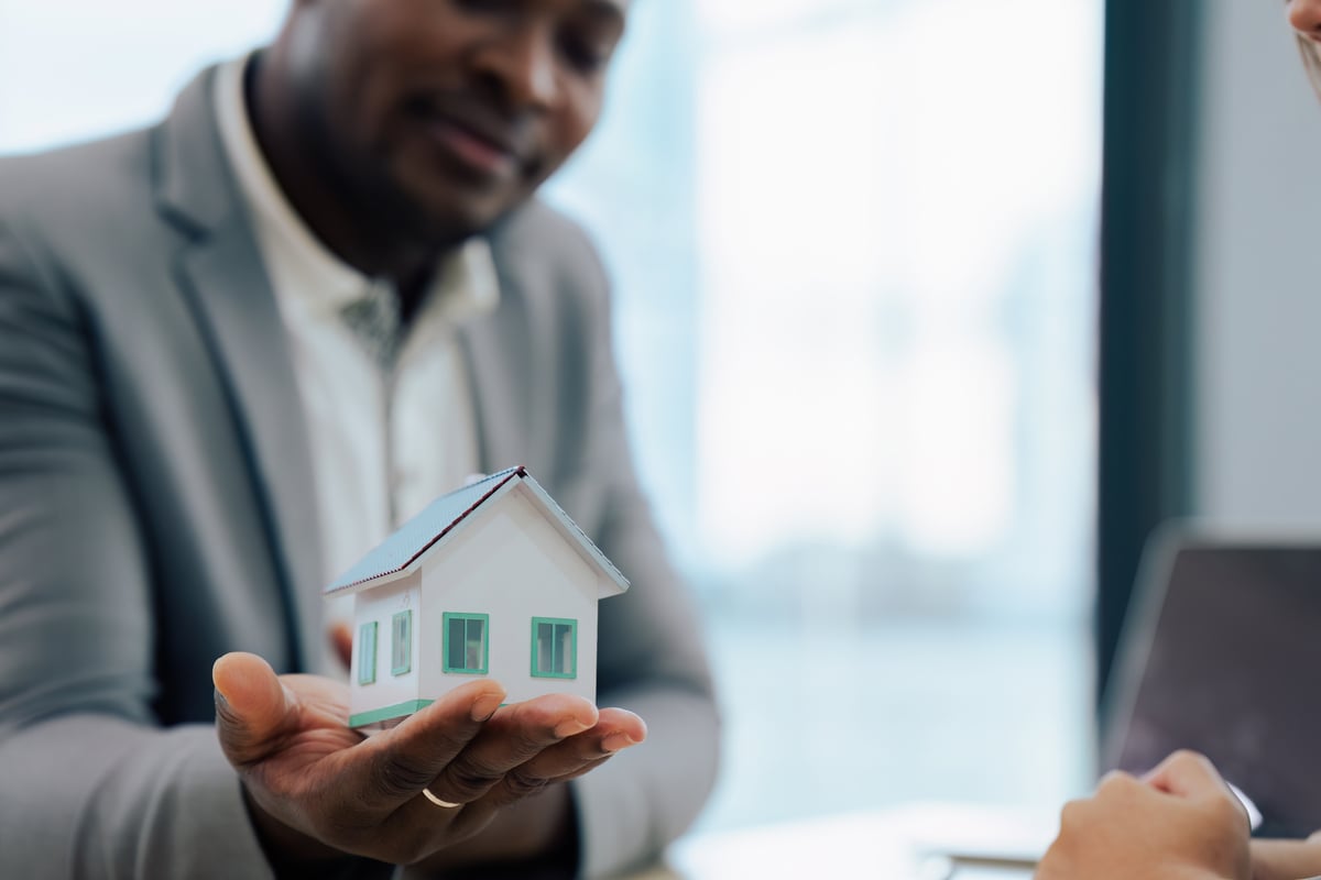 A man in a suit holding a small home