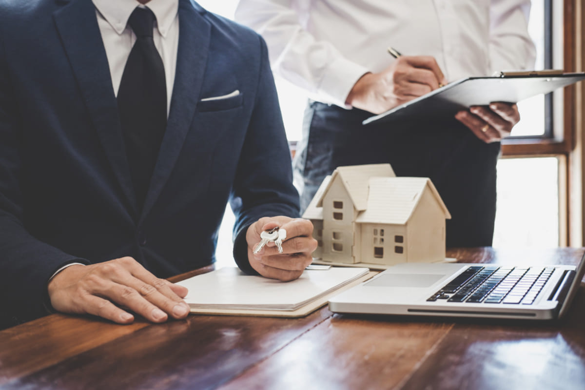 A man in a suit with keys next to model houses