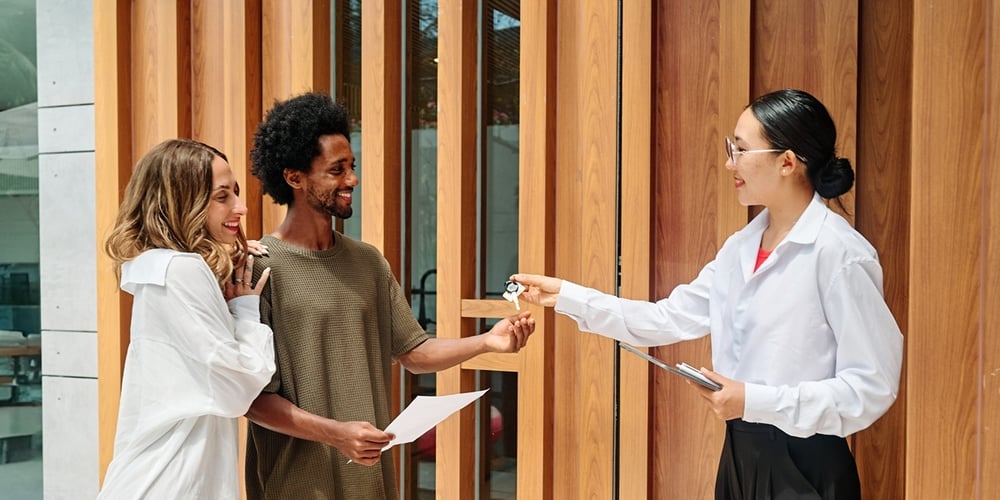 A real estate agent handing keys to new tenants