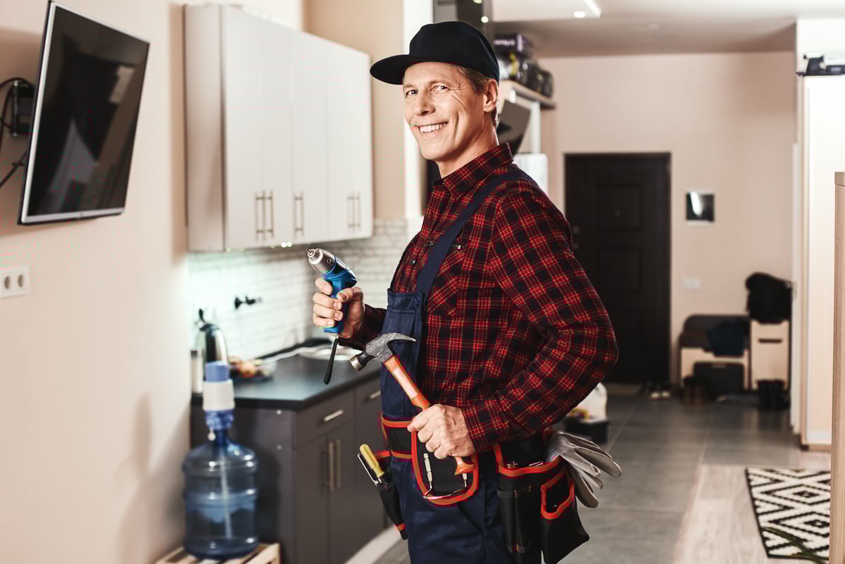 A repairman with a tool belt and tools in a home