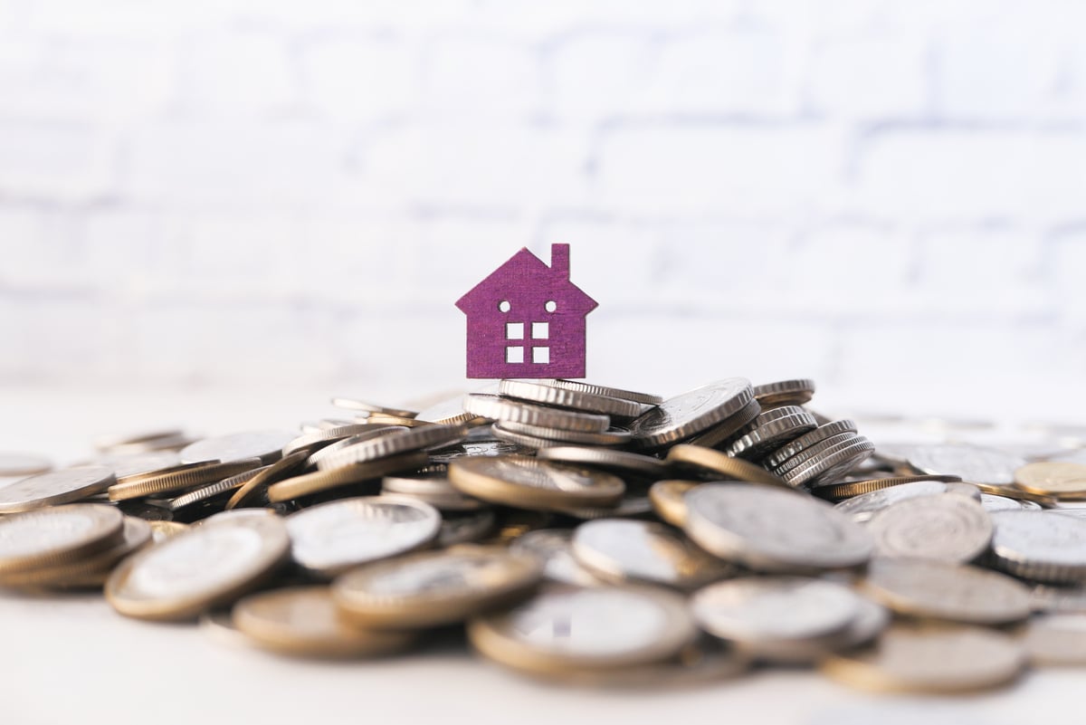 A small house on top of a pile of coins