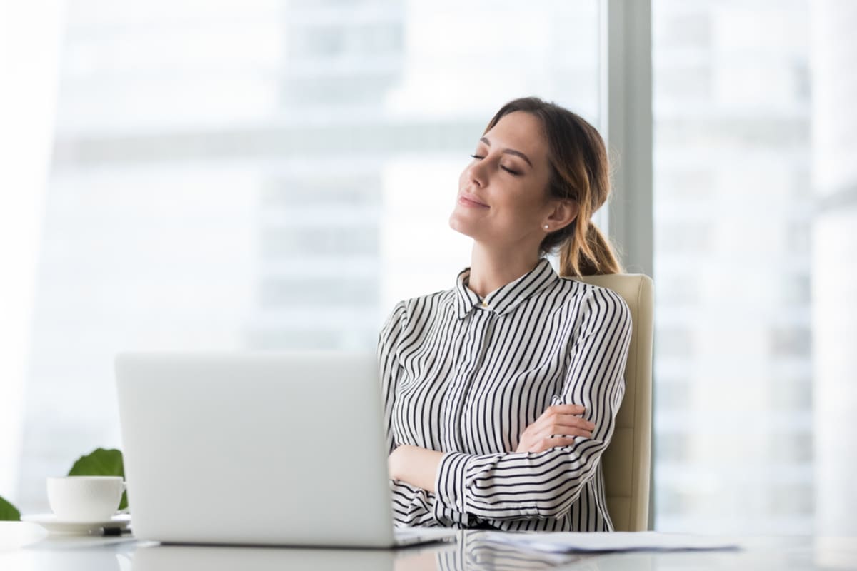 A woman relaxed and smiling in front of her laptop