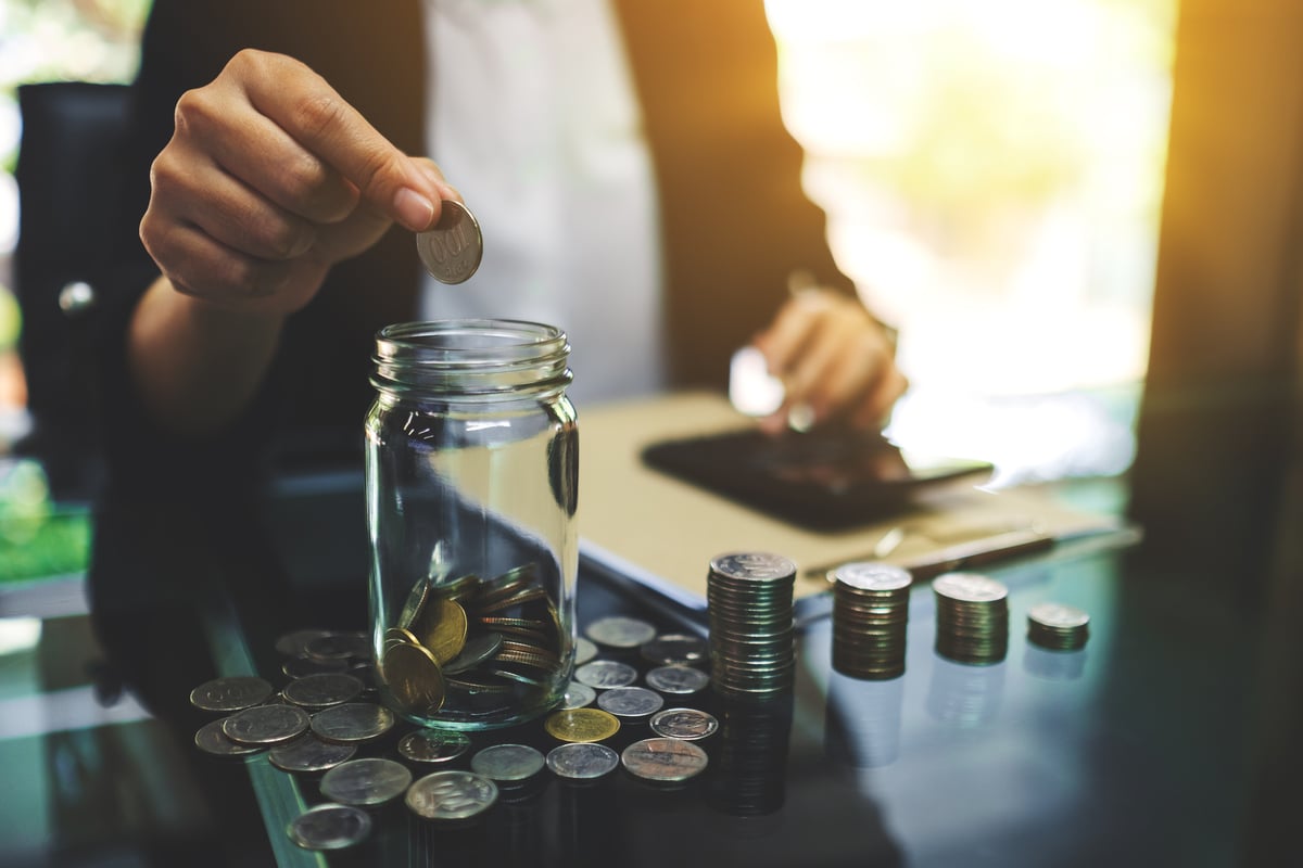 Coins being collected in a jar by a business professional
