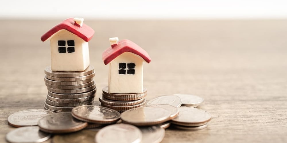 Coins stacked next to small models of houses