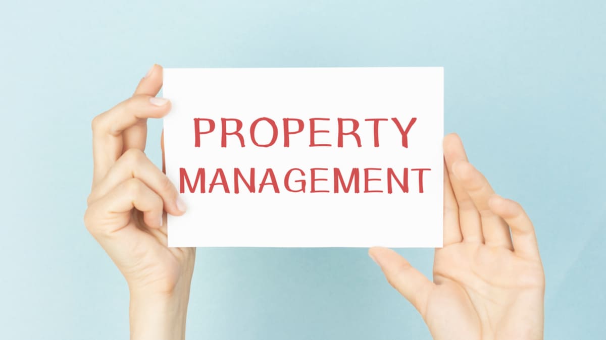 Hands holding a sign that says property management