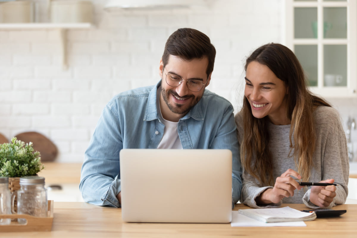 Happy tenants sitting at a laptop in their home