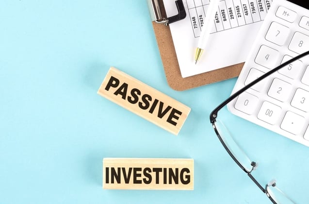 Passive investing on wood blocks next to glasses and a calculator