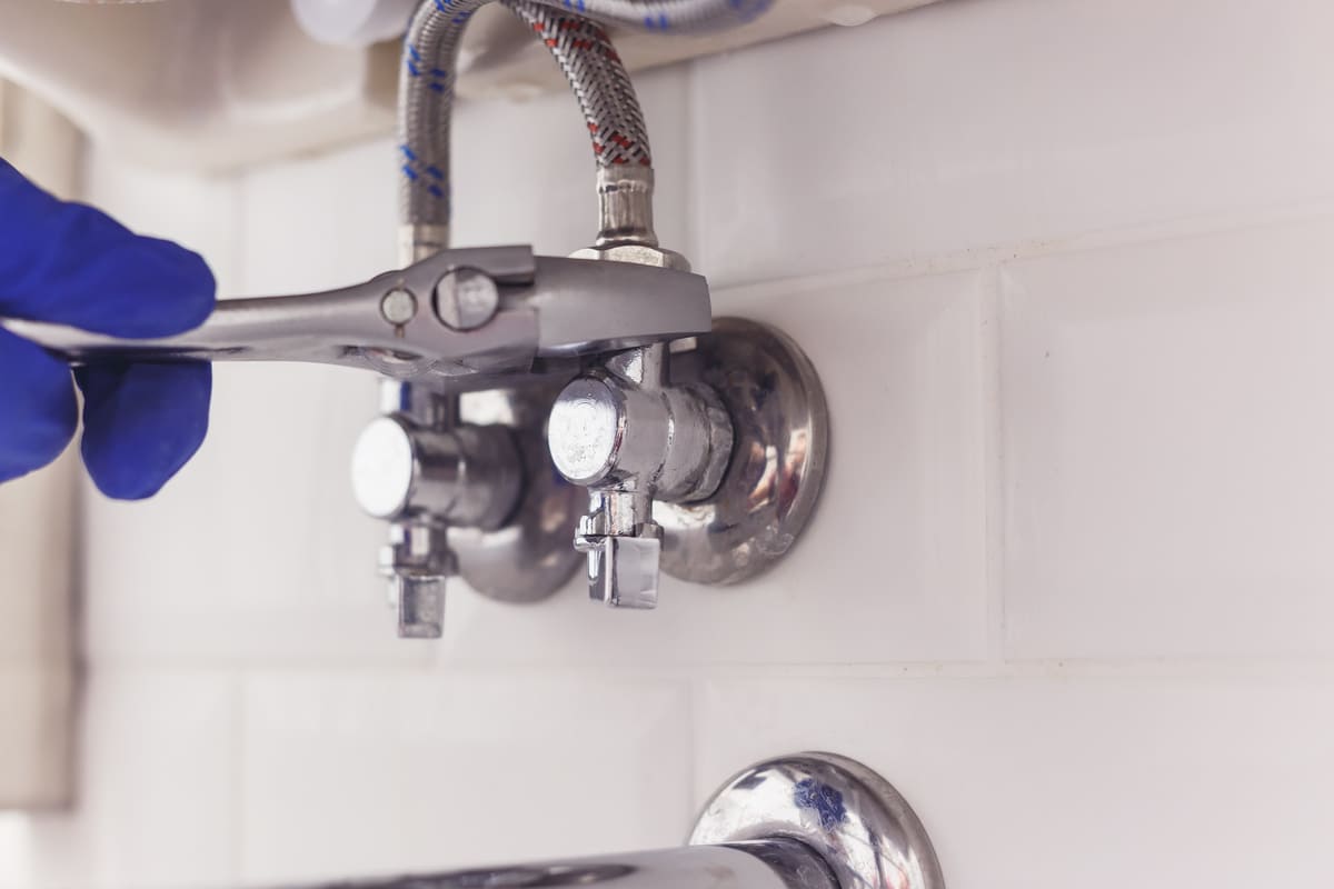 Plumber adjusting plumbing under a sink
