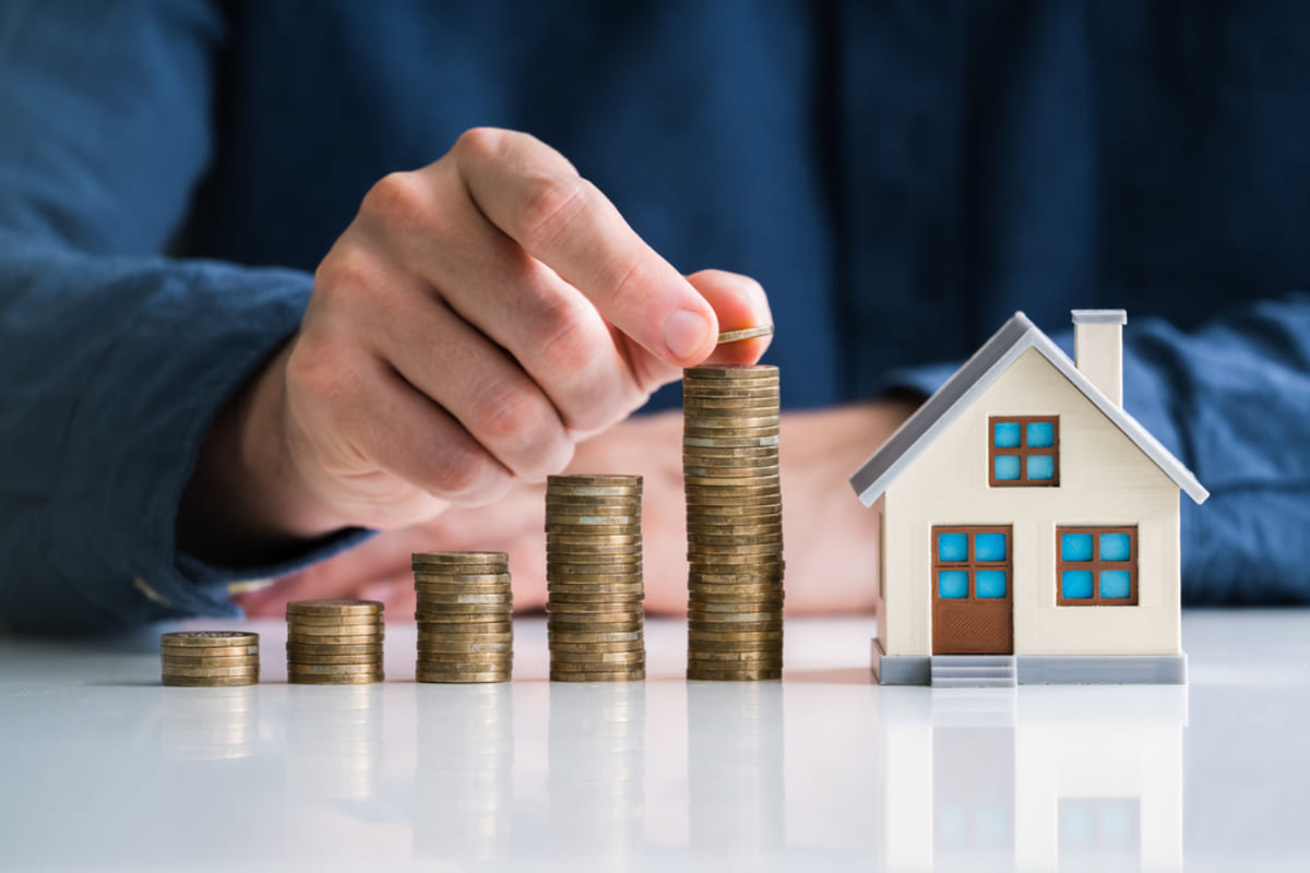 Stacking coins next to a model home