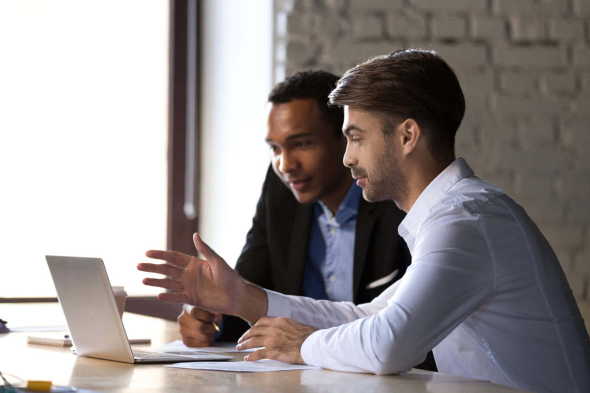 Two men using a laptop, learning from Detroit property management experts concept