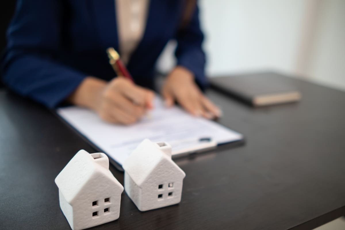 Two white model houses with a woman in the background, Detroit property management companies concept