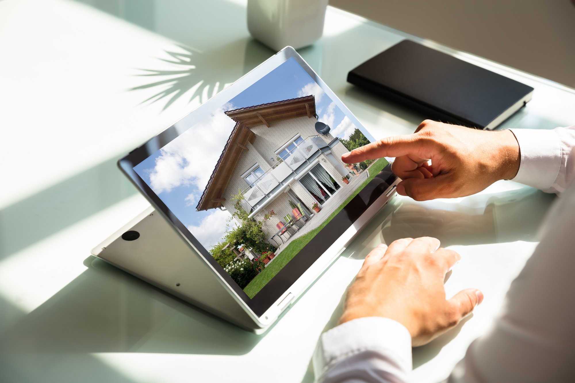 Close-up of businessmans hand checking house on laptop