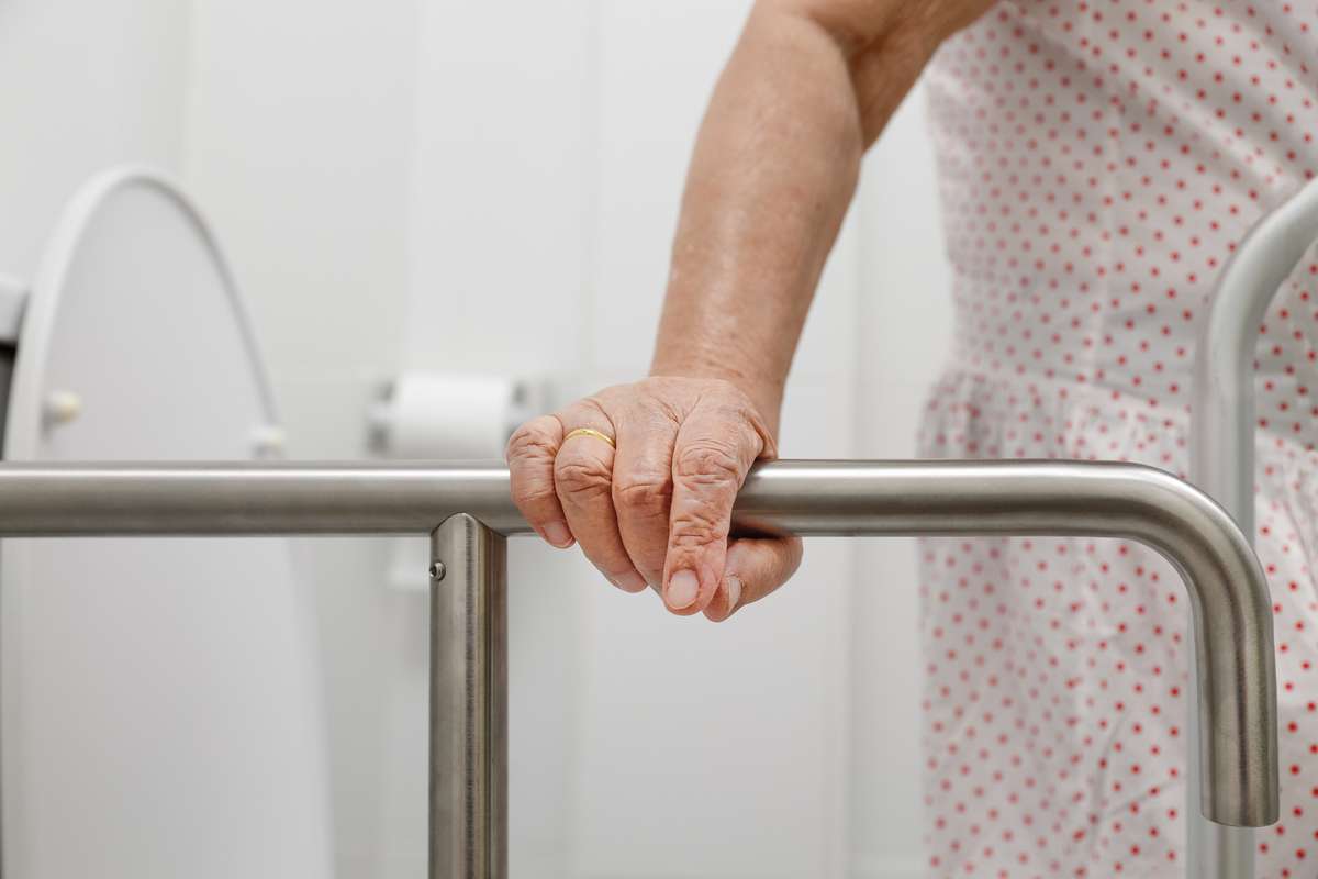 Elderly woman holding on handrail in toilet (R) (S)