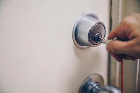 A hand inserting a key into a door lock, Detroit real estate investing concept. 