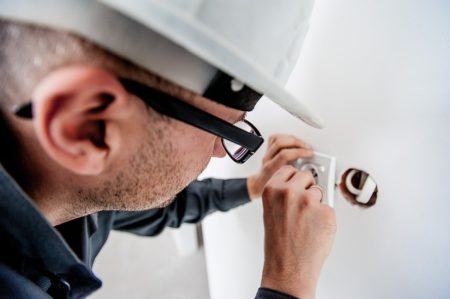 An electrician repairs a wall outlet to comply with Michigan landlord-tenant law. 