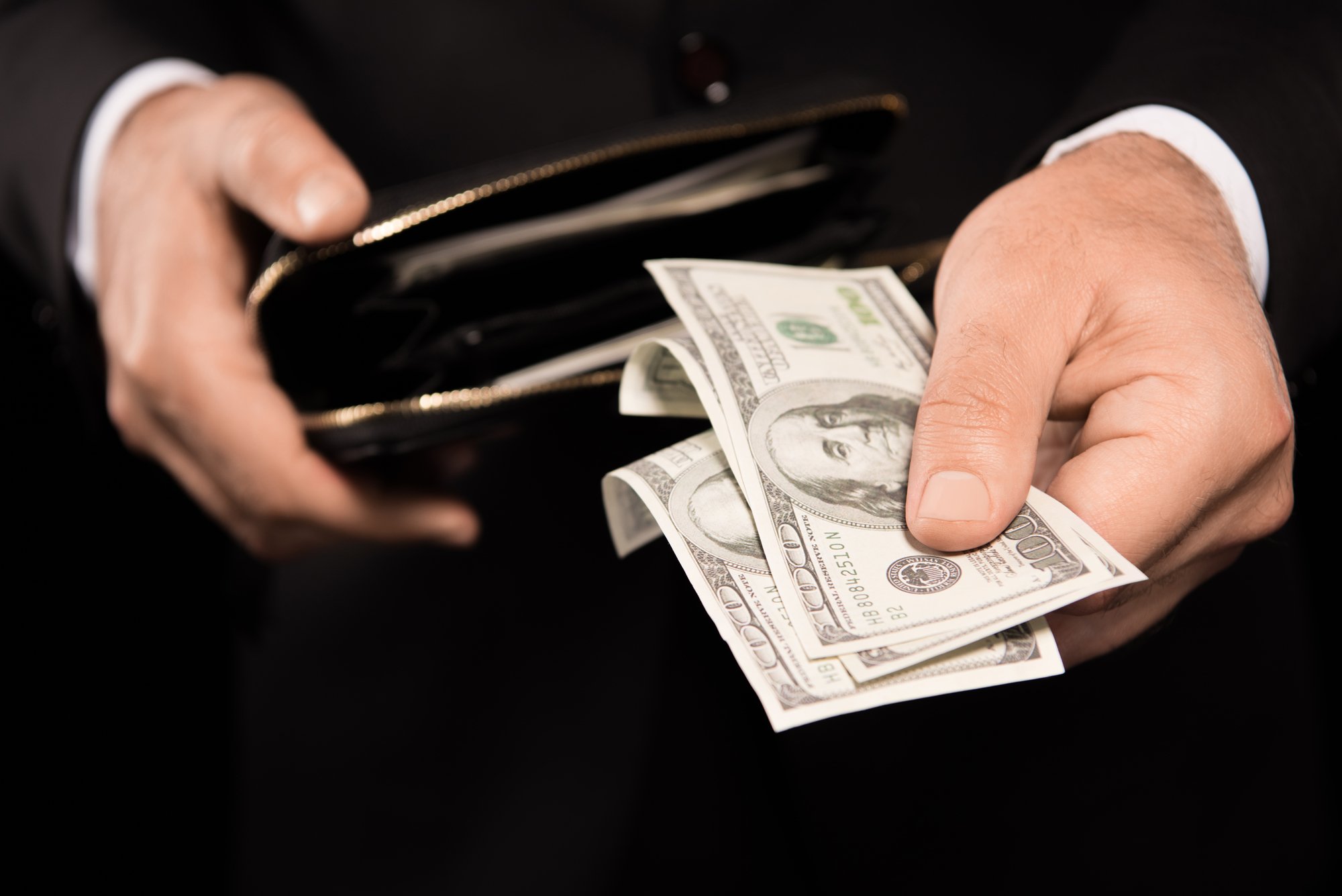 Male hands taking money from wallet, detroit rental property management concept. 