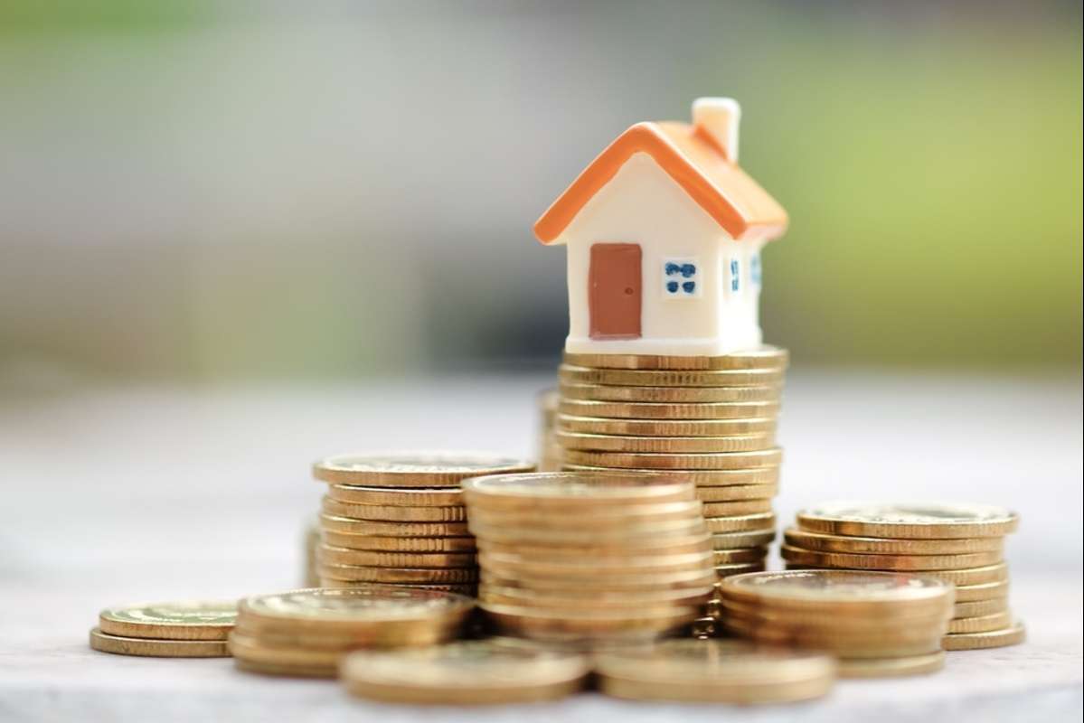 Mini house on stack of coins, rental property ROI concept. 