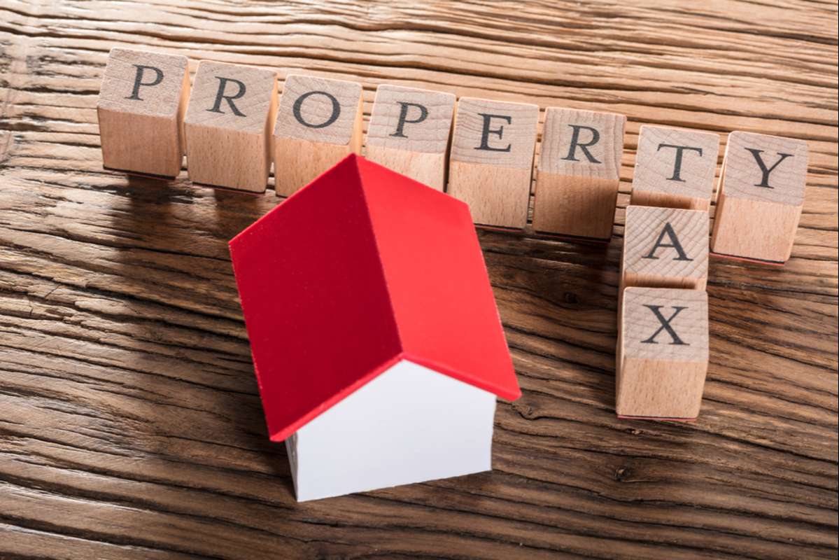 Property Tax Wooden Blocks With A Miniature House On Wooden Table