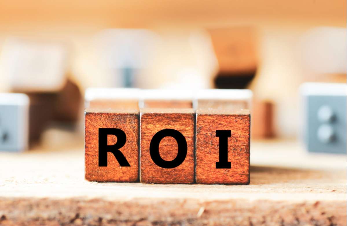 Wooden cubes with letters ROI, real estate investing ROI concept. 