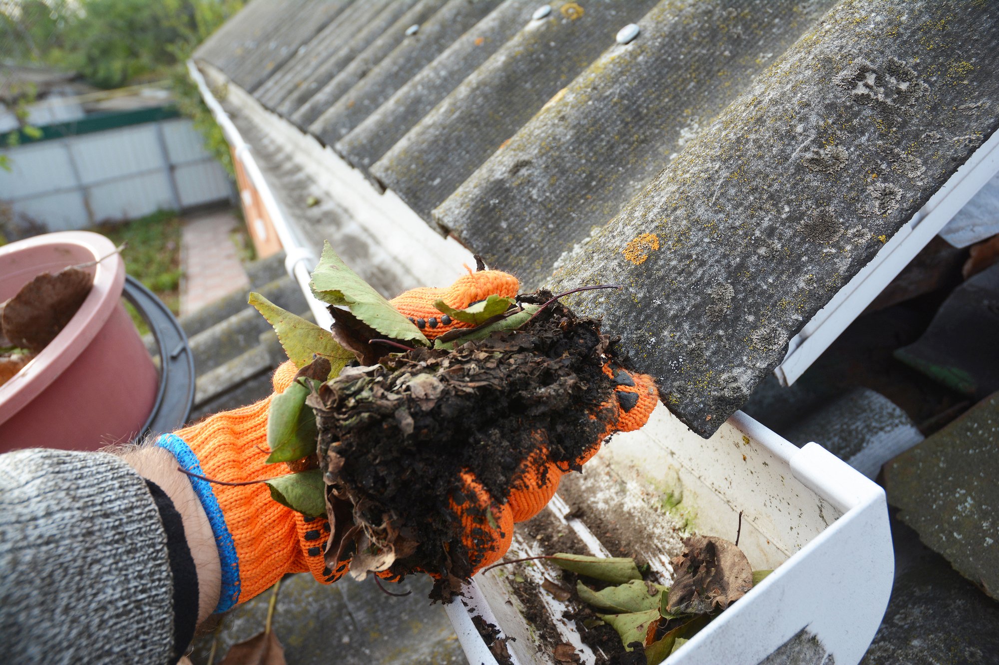 Rain Gutter Cleaning. Scooping leaves from gutter. Clean and Repair Rain Gutters