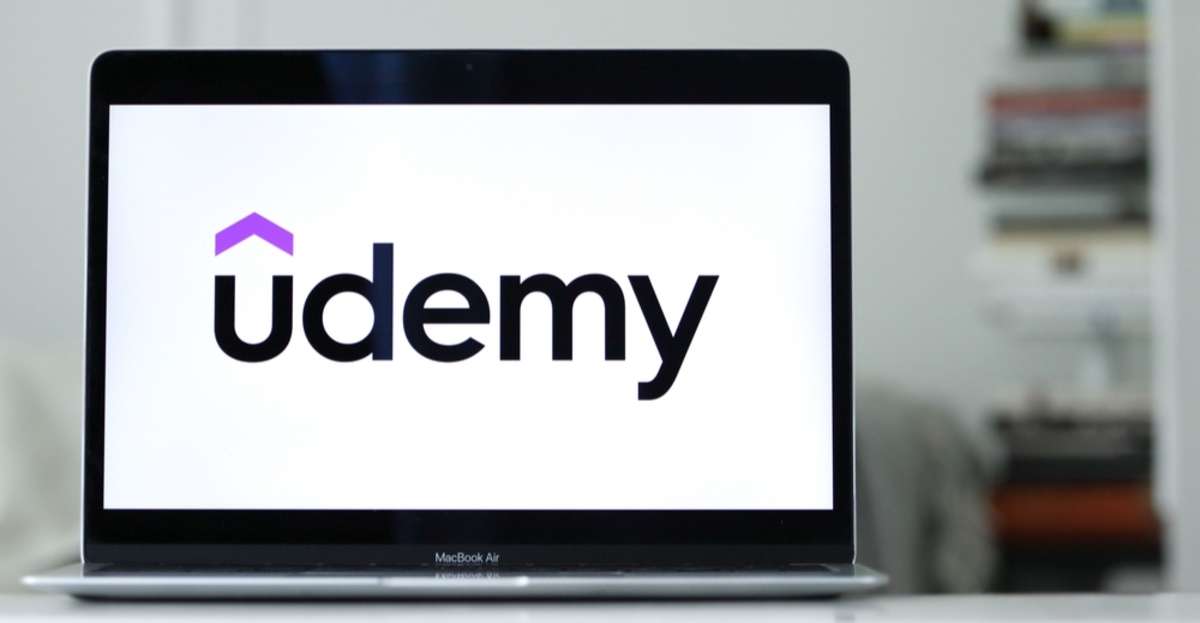 A laptop screen with the Udemy logo, real estate investing course concept