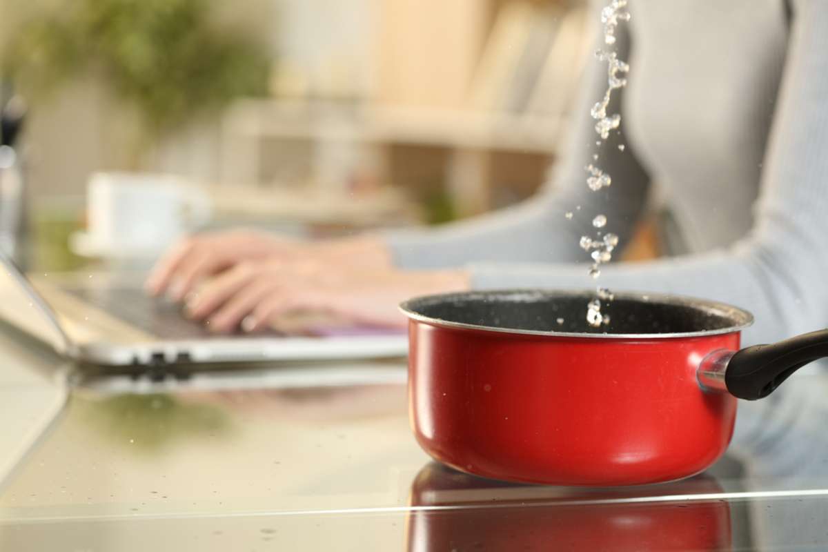 Close up of woman hands typing on laptop suffering water leaks falling on a pot