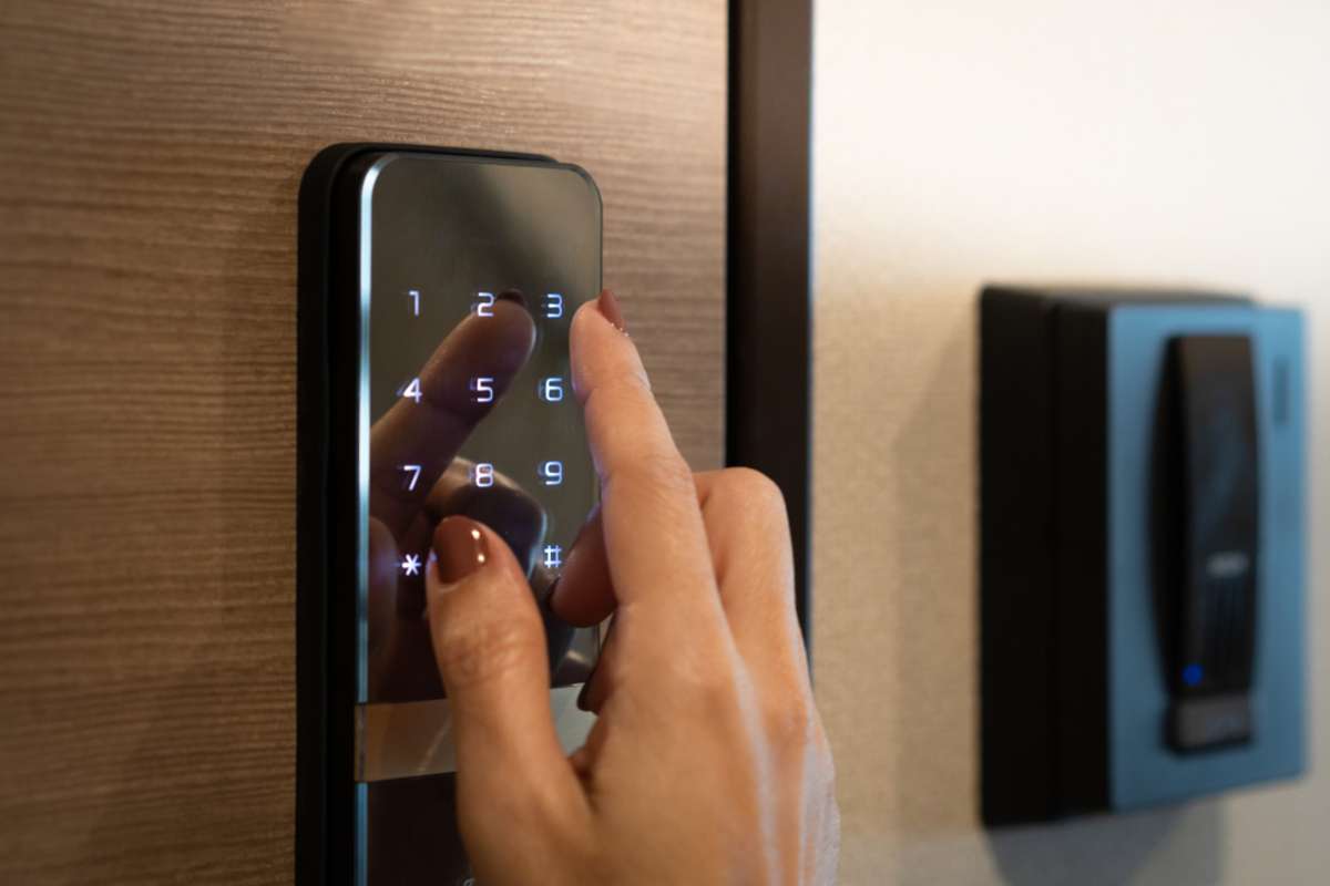 Closeup of a womans finger entering password code on the smart digital touch screen keypad entry door lock in front of the room