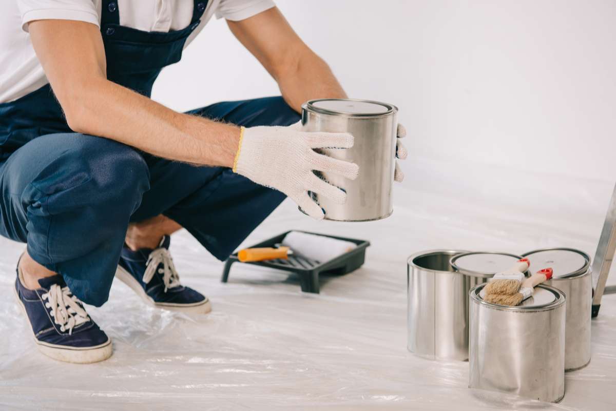 Cropped view of painter in uniform holding can with paint