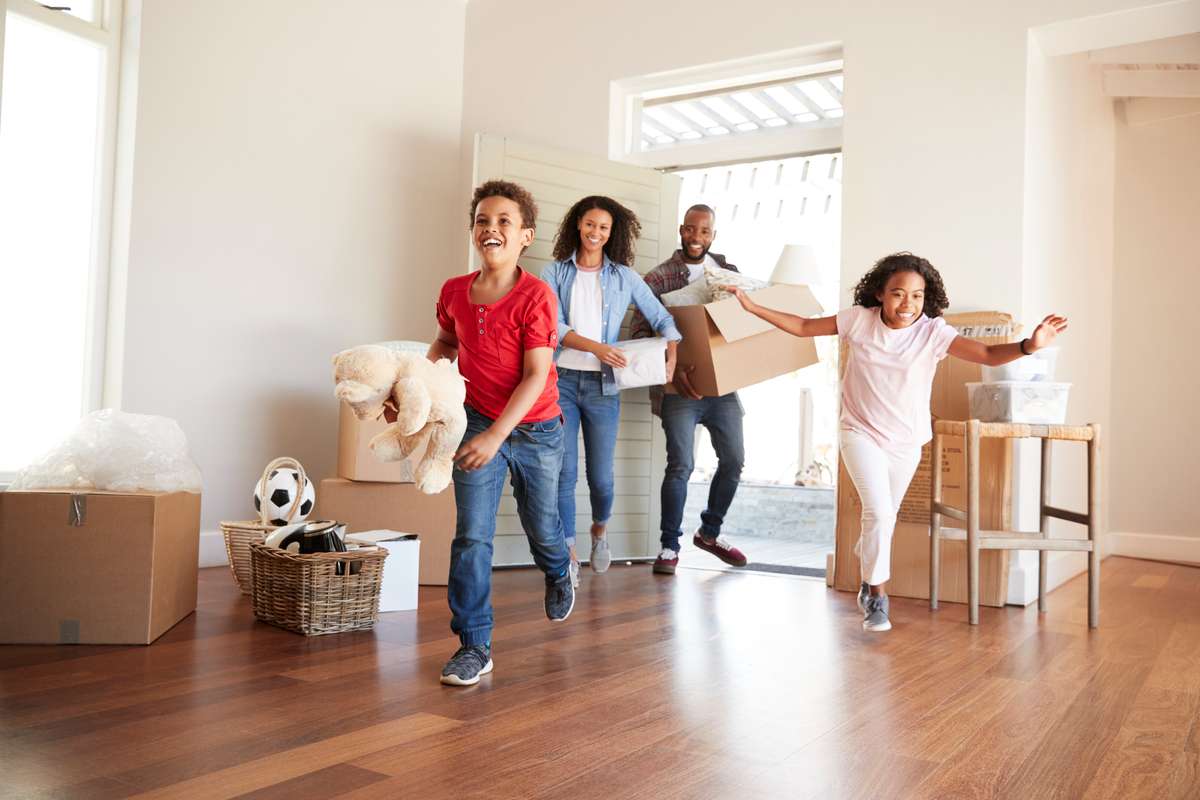 Excited Family Carrying Boxes Into New Home On Moving Day