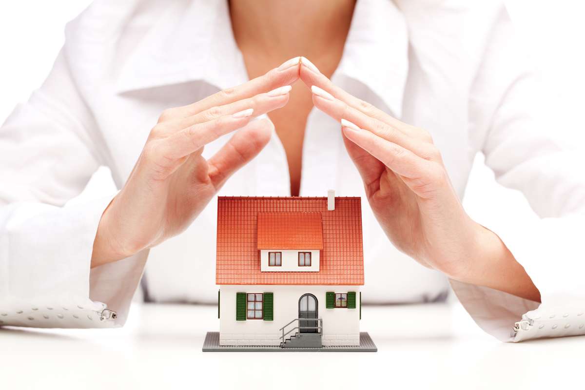 Female hands saving small house with a roof