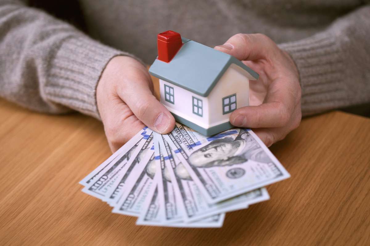 Hands holding dollars and the layout of the house