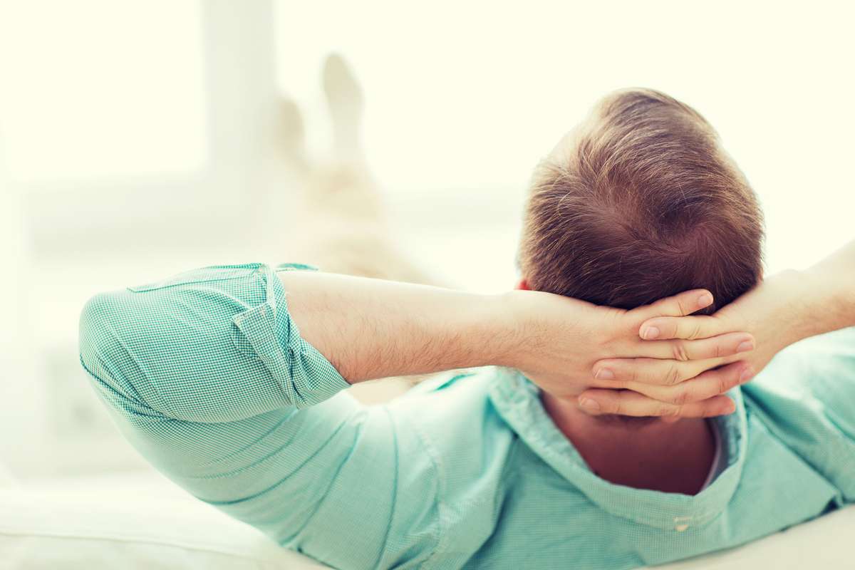 Man lying or sitting on sofa at home from back