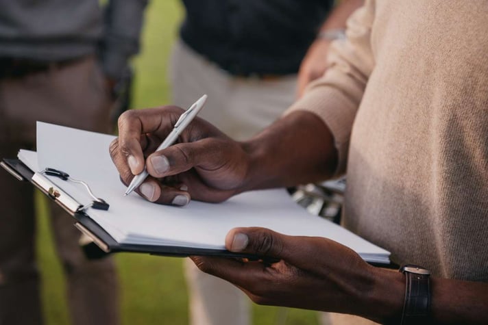Man writing on paper in clipboard