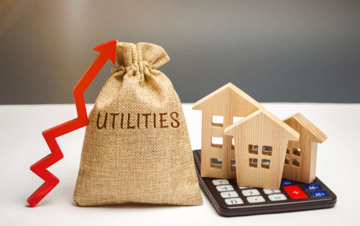 Money bag with the word Utilities and an up arrow and houses on a calculator