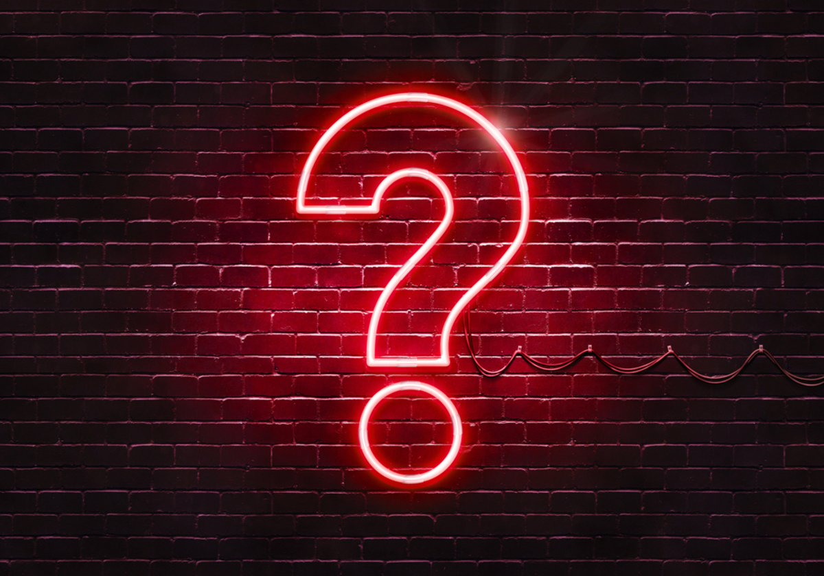 Neon sign on a brick wall in the shape of a question mark