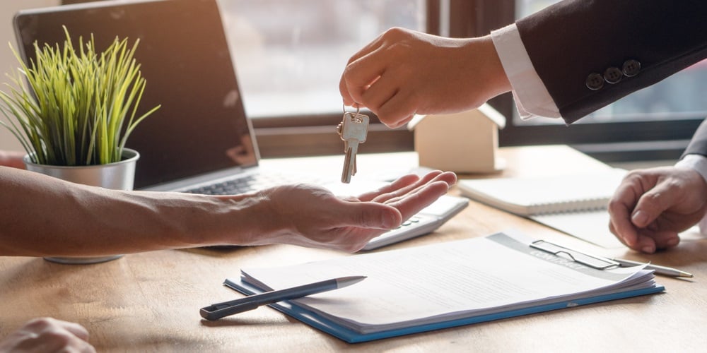 Realtor agent giving a key of apartment to new owner after signed lease agreement