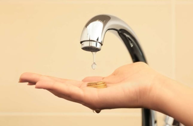 Woman holding coins under metal tap, closeup