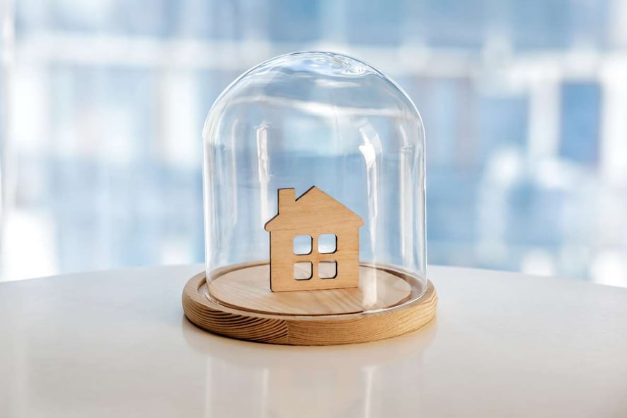Wooden model of house under glass cap Symbol of safe home. Insurance or protecting building property concept