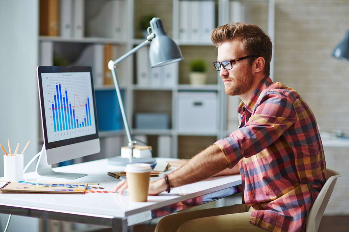 Young man looking at financial chart reflecting changes in market development