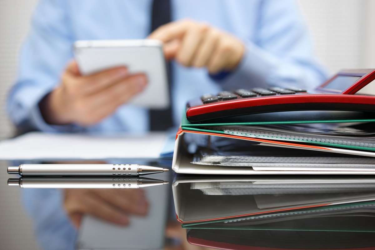 files and folders and businessman in background with tablet pc in hands