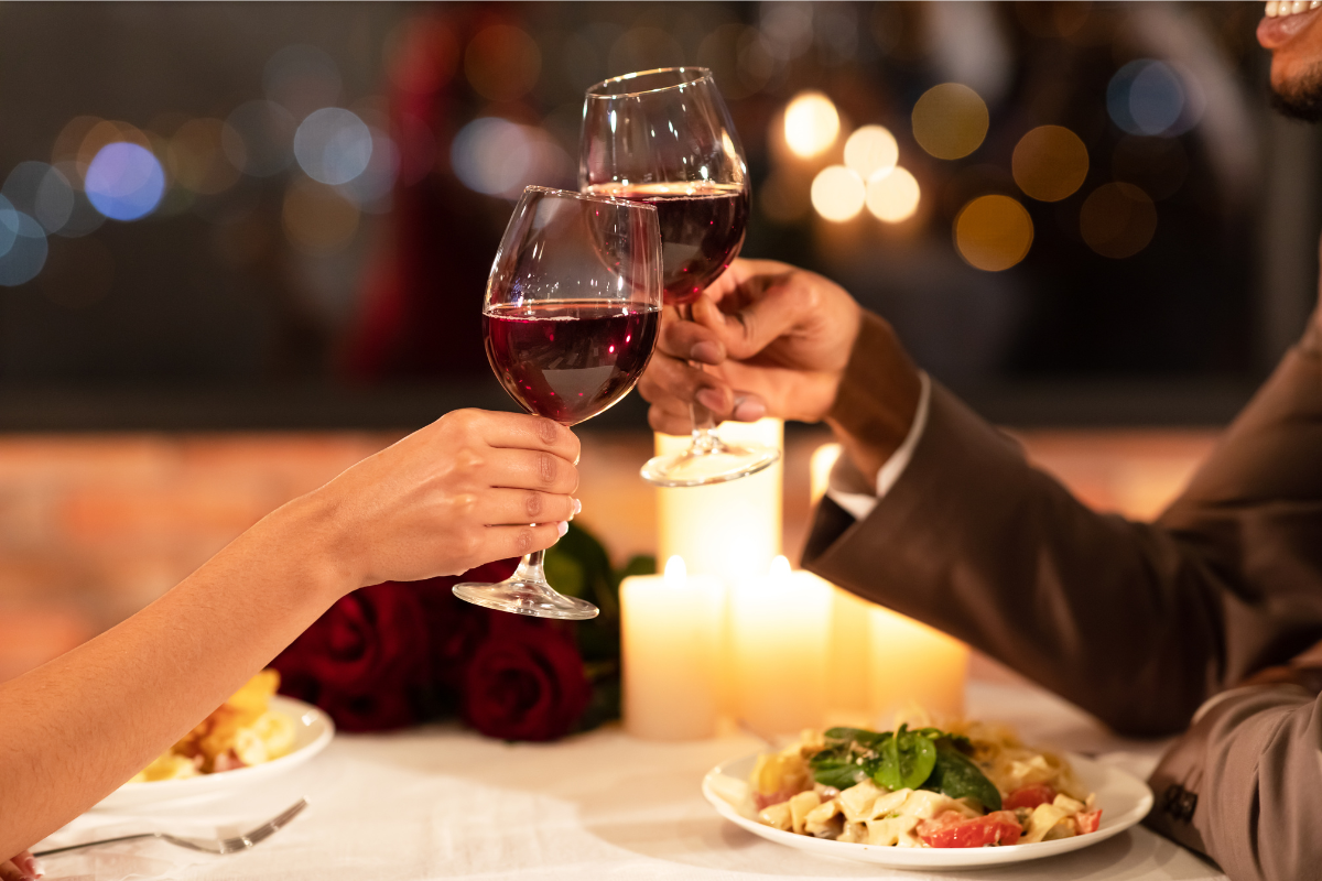 Two people toasting wine glasses at dinner