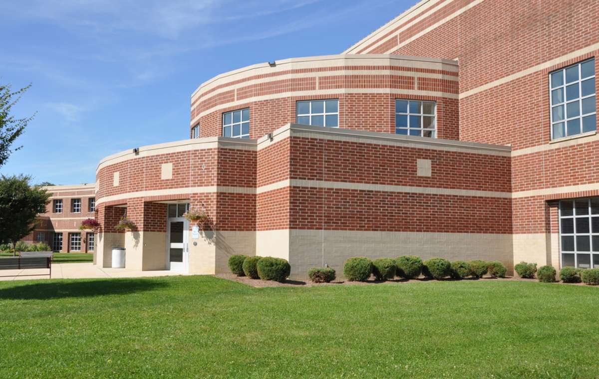 exterior of a modern brick high school by a lush green lawn