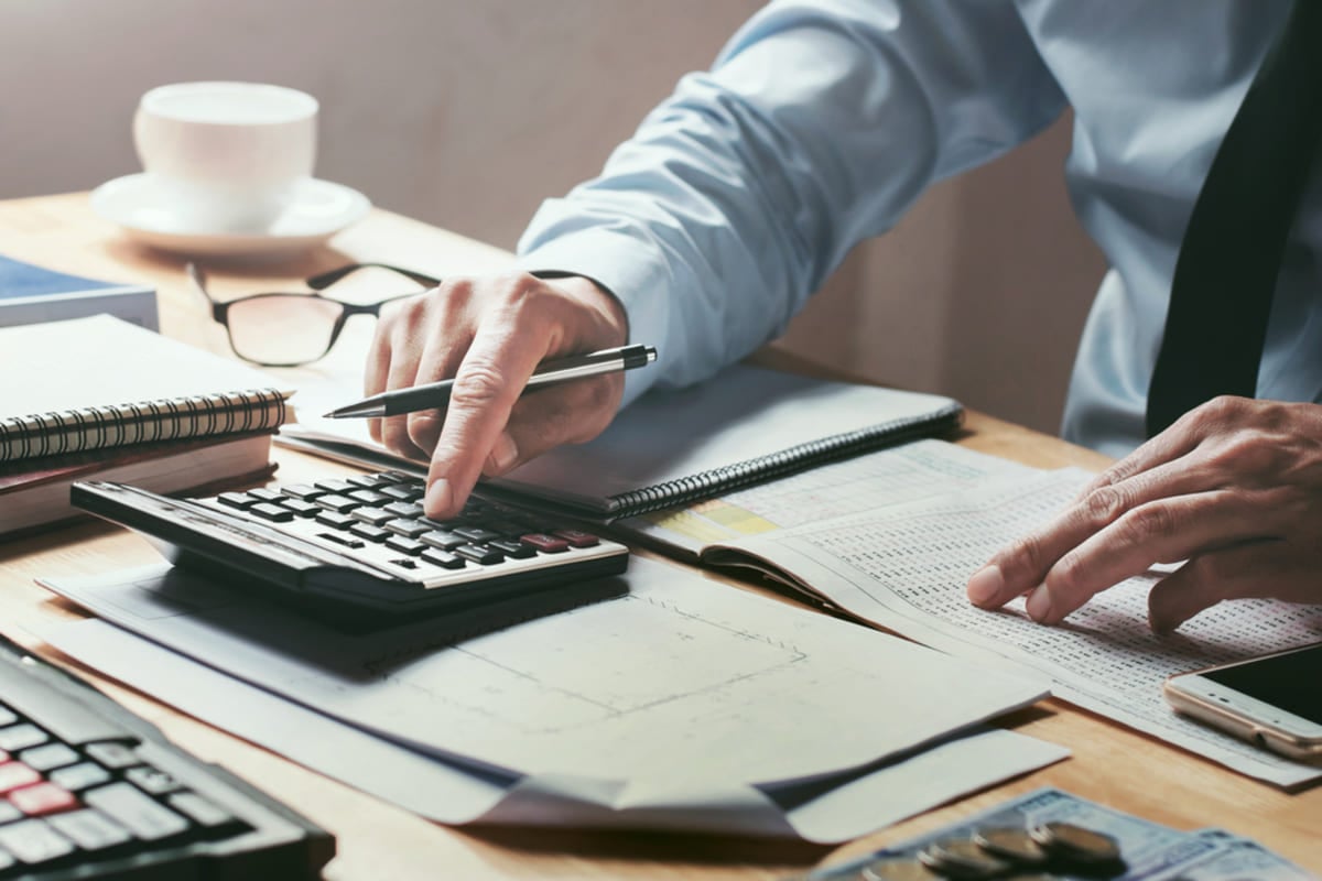 A man in a suit typing on a calculator