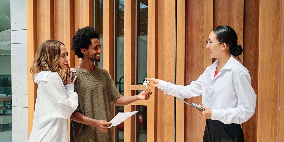A real estate agent handing keys to new tenants