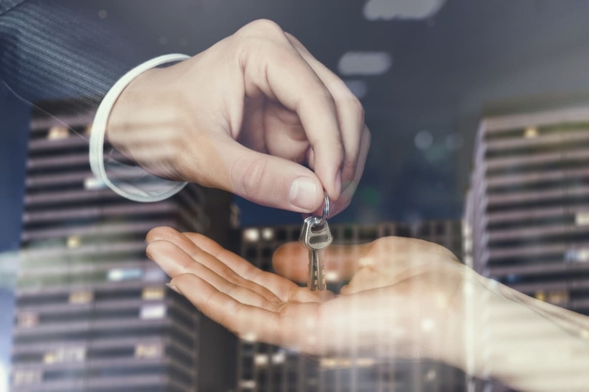 Businessman handing someone a key with city overlay