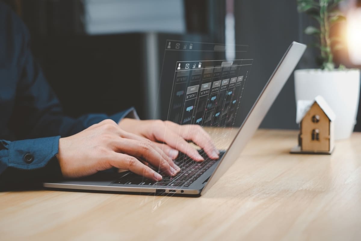 Someone working on a computer and looking at data next to a model home