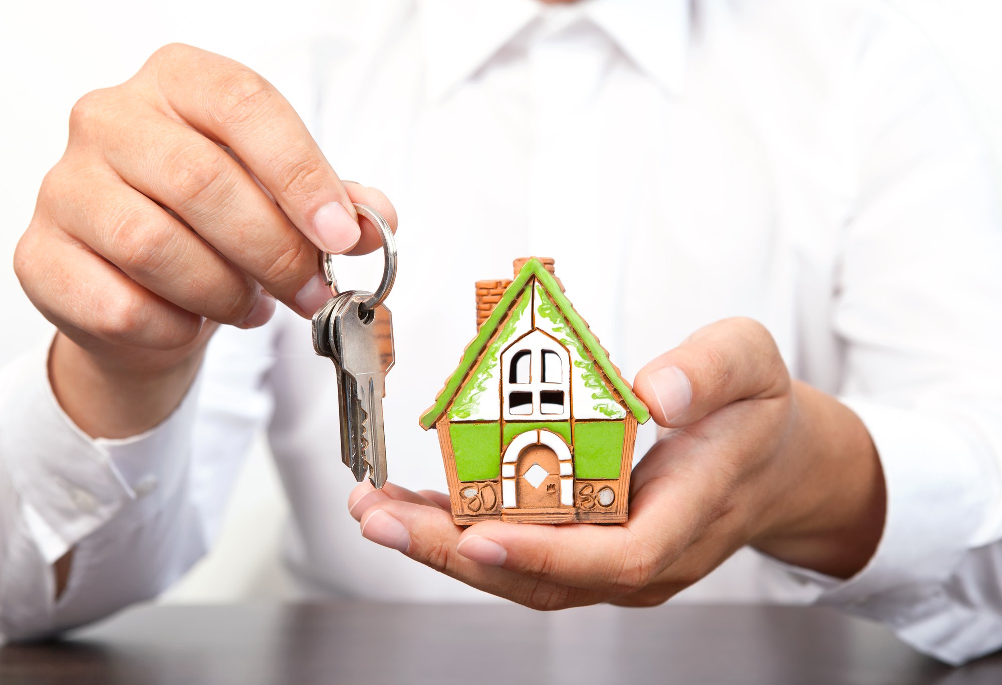 Hand holding a set of keys and a miniature house 