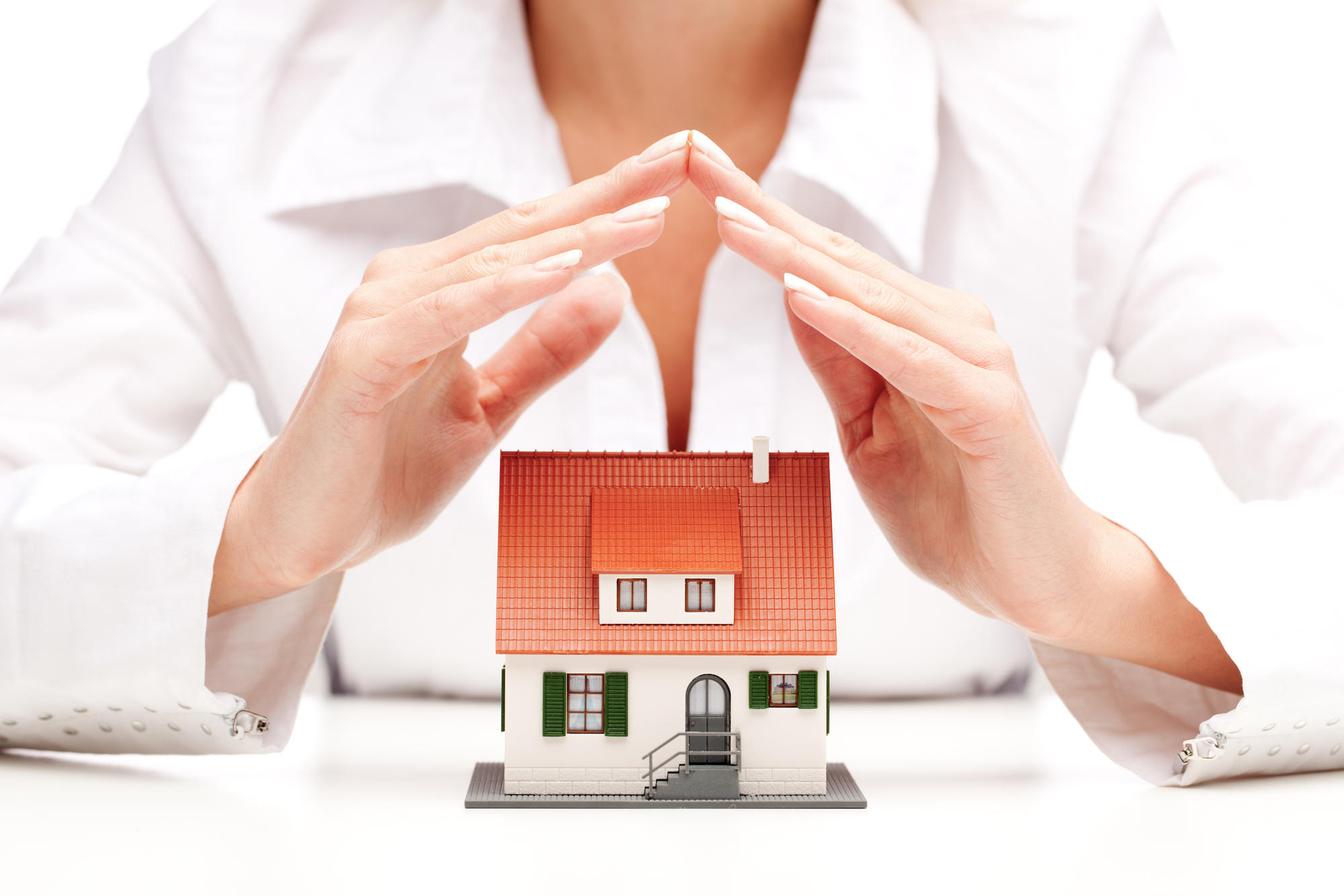 Tiny house model with a pair of hands over it portraying house protection